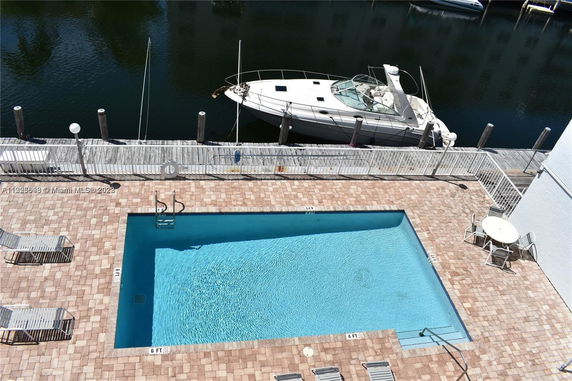 Outdoor view of a swimming pool next to a waterfront with a docked boat.