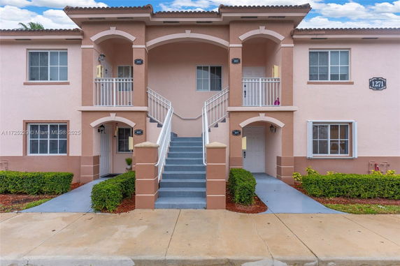 Front view of a two-story residential building with stairs leading to upper floor units.