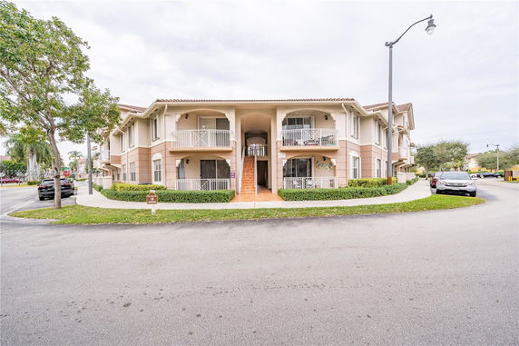 Front view of a two-story residential building with balconies and an arched entrance.