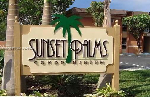 Front view of Sunset Palms condominium sign with building in the background.