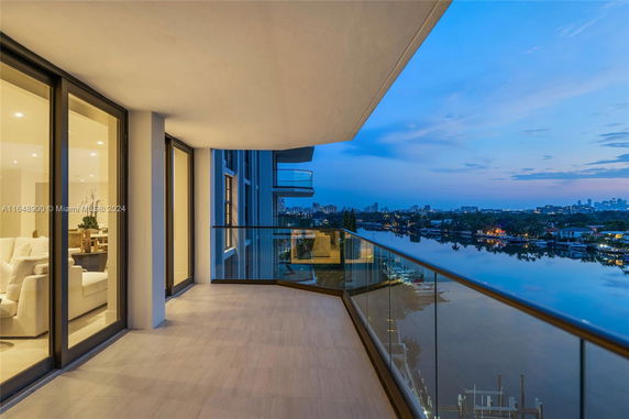 Wide-angle view from a balcony overlooking a body of water and city skyline at dusk.