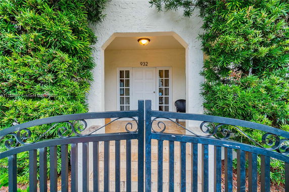 Front view of a house entrance with a gated archway and green foliage.