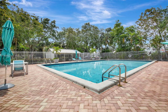 Outdoor swimming pool area with surrounding trees and a fence.