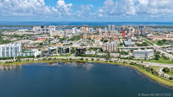 Aerial view of a cityscape with various buildings and a large body of water in the foreground.