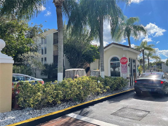 Outdoor view of a building entrance area with a small guardhouse and a stop sign.