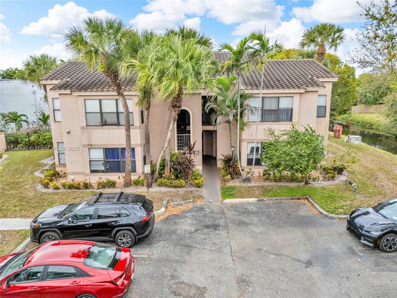 Front view of a two-story residential building with parked cars.