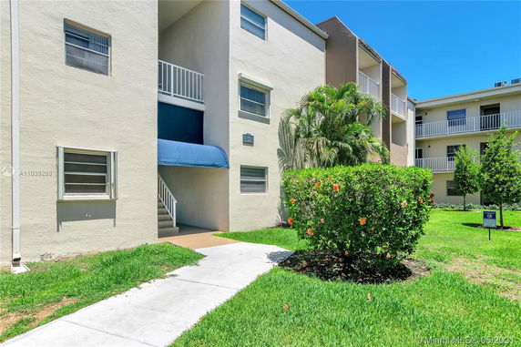 Front view of a multi-story apartment building with balconies and a covered entrance.