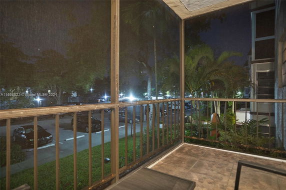 View from a screened balcony overlooking a parking area at night.