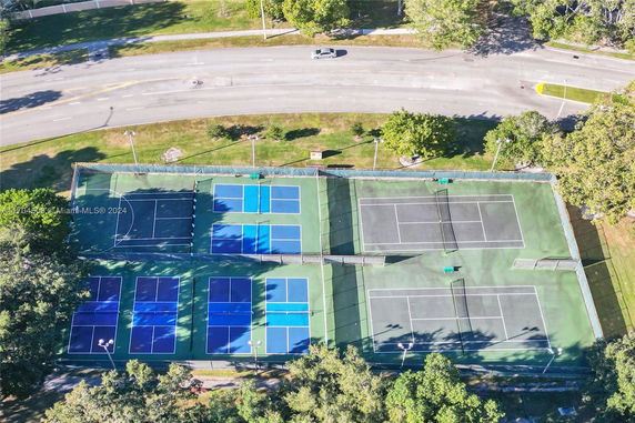 Aerial view of a complex with multiple tennis courts surrounded by greenery.