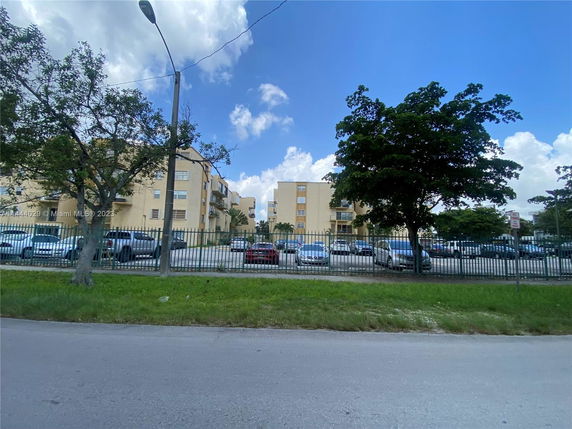 Front view of a multi-story apartment building with parking area.