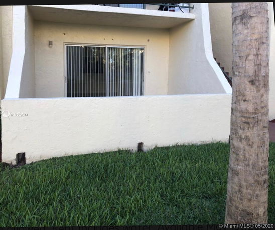 Front view of a building with a patio and sliding glass door.