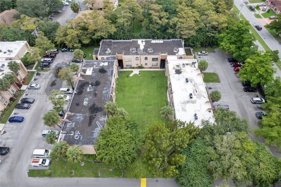 Aerial view of an apartment complex with surrounding parking and trees.