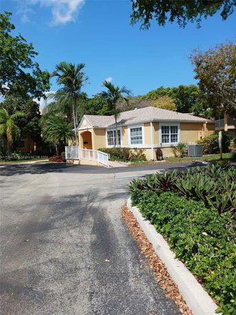 Front view of a single-story house with beige exterior and a ramp leading to the entrance.