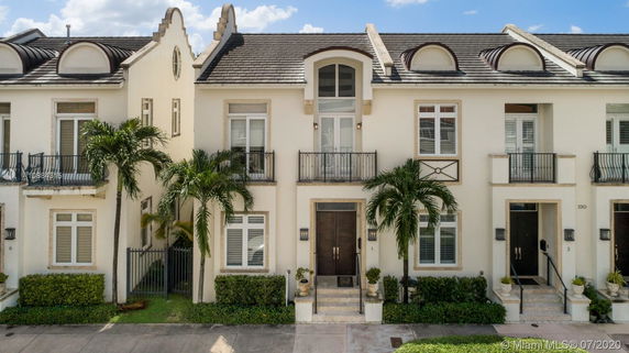 Front view of a two-story townhouse with decorative roof elements and balconies.
