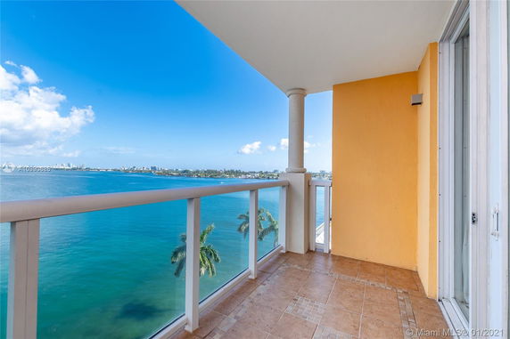Balcony view overlooking a body of water with a cityscape in the distance.