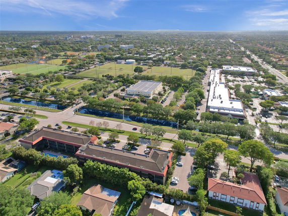 Aerial panoramic view of a suburban area with buildings, roads, and green spaces.