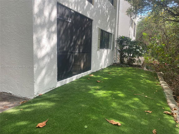 Side view of a building with artificial grass and windows.