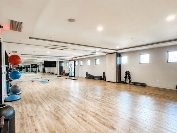Spacious indoor gym area with wooden flooring and exercise equipment.