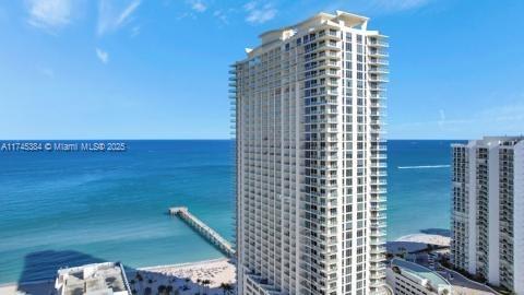 High-rise building near the ocean with a pier extending into the water.
