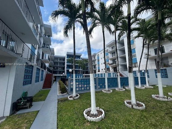 Outdoor view of apartment buildings with balconies and palm trees.