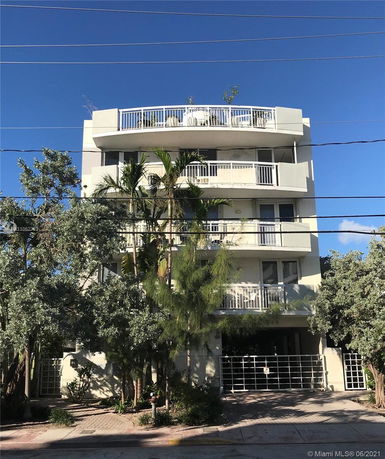 Front view of a multi-story building with balconies and a gated entrance.