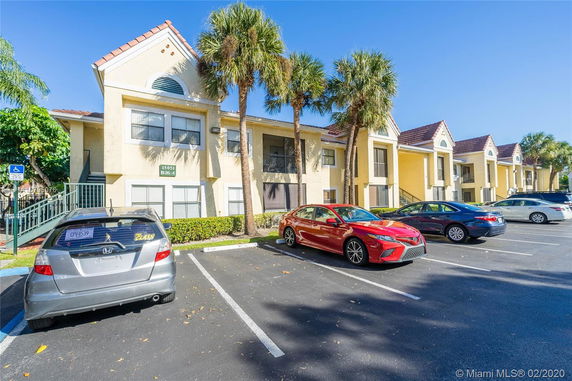 Front view of a two-story residential building with parked cars.
