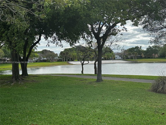 View of a lake with trees and houses in the background.