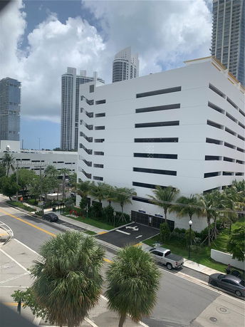 Multi-story parking garage in an urban area with tall buildings in the background.