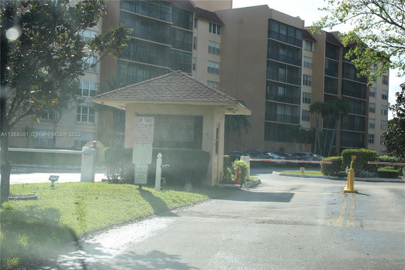 View of a parking area near a multi-story building with a small security or toll booth.