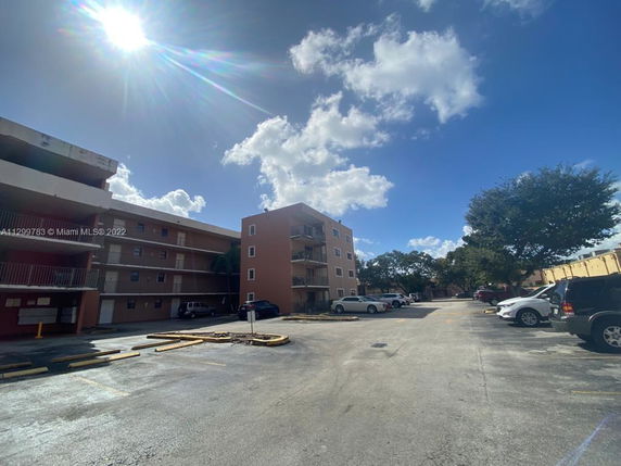 Outdoor parking area with a multi-story residential building.