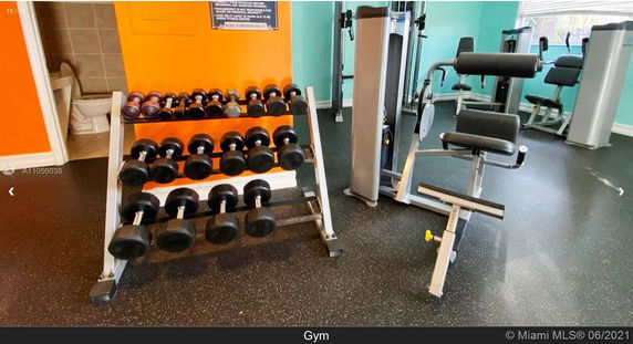 Indoor gym area with exercise equipment and weights.
