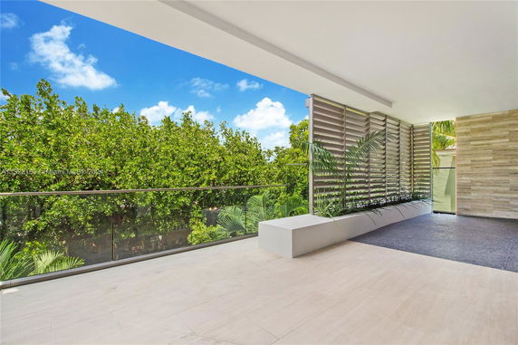 Panoramic view from a balcony with glass railing and lush greenery.