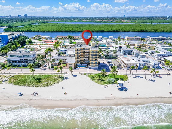 Aerial view of a beachfront area with multiple buildings along the shoreline.
