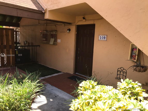 Entrance view of a building unit with visible door number 109 and plants nearby.