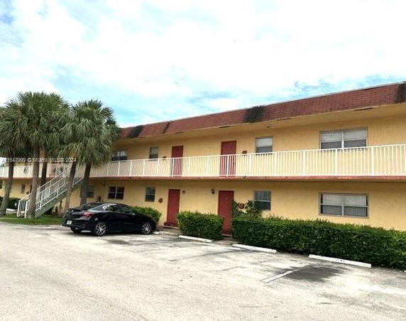 Front view of a two-story building with balconies and parking space.
