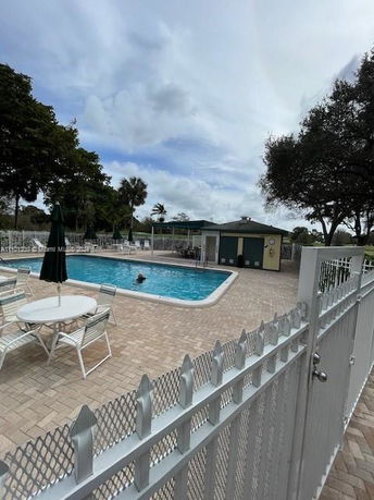 Outdoor swimming pool area with surrounding chairs and tables.
