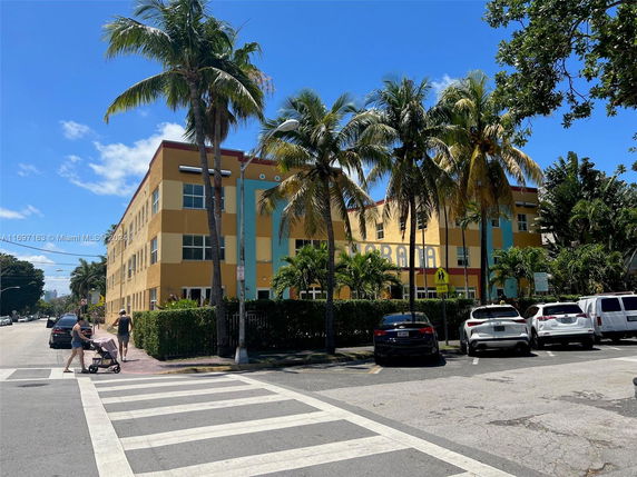 Front view of a multi-story building with colorful exterior and palm trees in front.