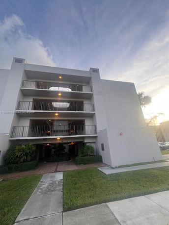 Front view of a multi-story building with balconies and a landscaped entrance.