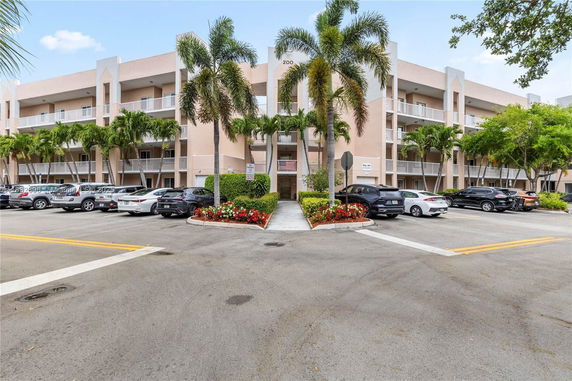 Front view of a multi-story building with balconies and parking area.