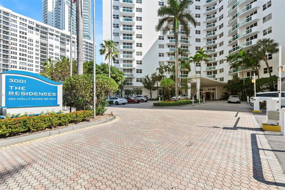 Front view of a high-rise residential building with a driveway and entrance area.