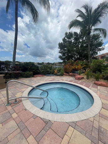 Small circular outdoor pool with surrounding palm trees and patio.