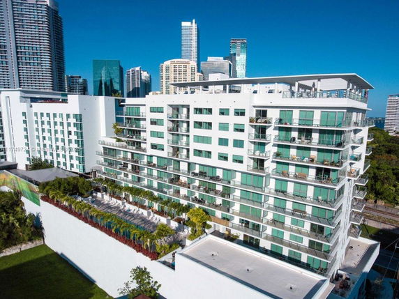 Front view of a multi-story apartment building with balconies and rooftop features.