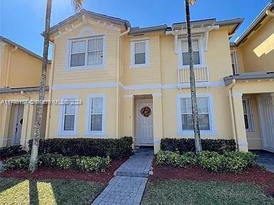 Front view of a two-story yellow townhouse with white trim.