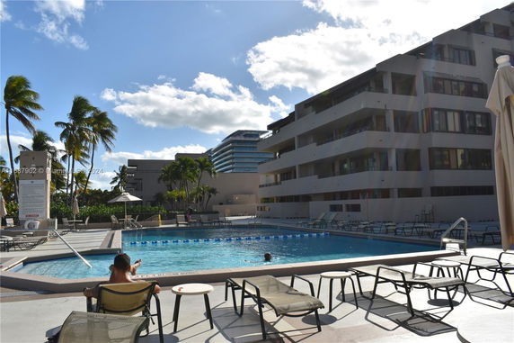 Outdoor swimming pool area adjacent to a multi-story building.