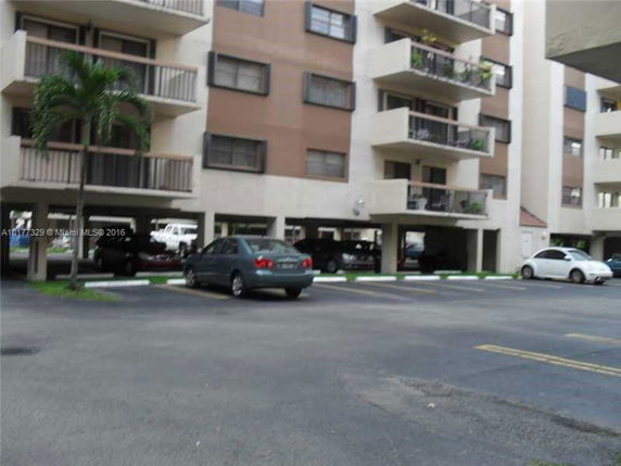 Front view of a multi-story residential building with parking area.