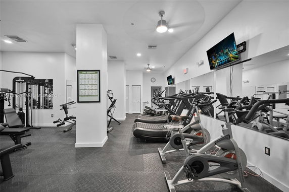 Interior view of a gym equipped with exercise machines and TVs.