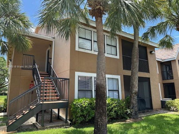 Front view of a two-story apartment building with an external staircase and balconies.