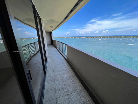 View from a balcony over a body of water with distant shoreline and clear sky.