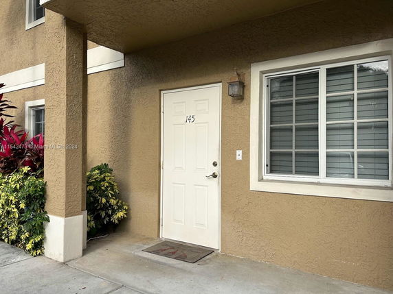 Front view of a building entrance with a white door and window.