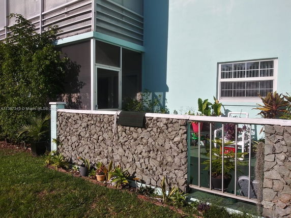 Partial view of a building with a stone and metal railing balcony and large windows.